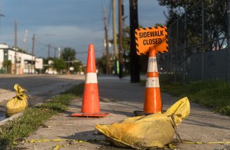 Orange traffic cones and closed sidewalk sign on urban street in Houston.