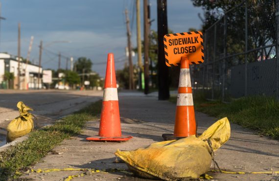 Orange traffic cones and closed sidewalk sign on urban street in Houston.
