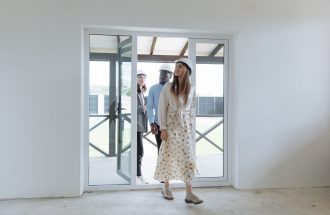 Group of architects walking through a bright new building, inspecting the interior space for construction evaluation.