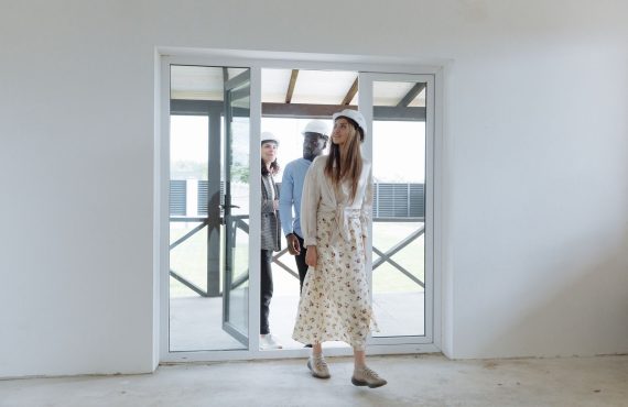 Group of architects walking through a bright new building, inspecting the interior space for construction evaluation.