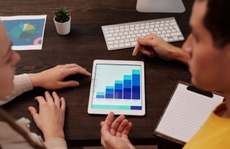 Team members discussing digital graphs on a tablet in a modern office setting.
