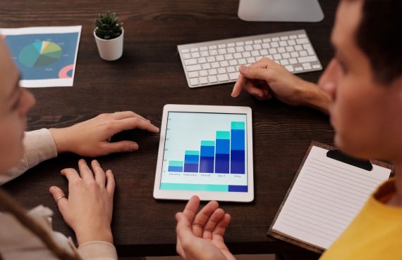 Team members discussing digital graphs on a tablet in a modern office setting.