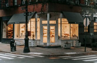 Facade of lit shop on street near crosswalk and roadway on street in modern city in soft daylight