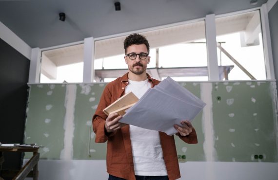 Architect holding and reviewing design documents in a modern interior setting.