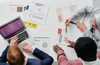 Business meeting with professionals discussing financial reports and graphs at a work desk.