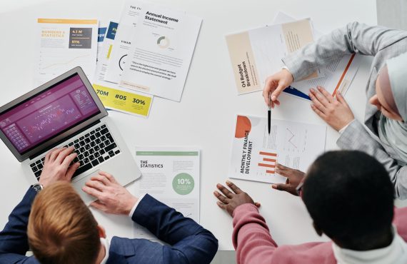 Business meeting with professionals discussing financial reports and graphs at a work desk.