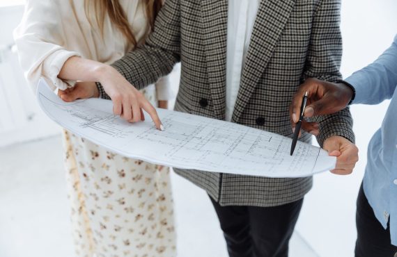 Adults reviewing detailed schematic floor plans indoors for a new building.