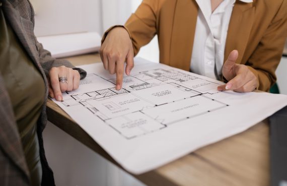 Two professionals reviewing architectural plans, focused on floor layout and design details.