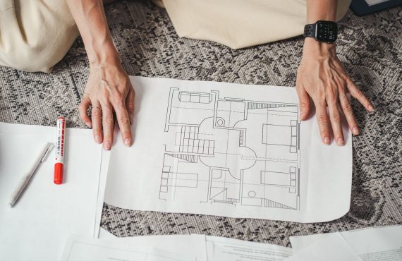 Hands on a detailed architectural floor plan paper, showcasing home design layout.