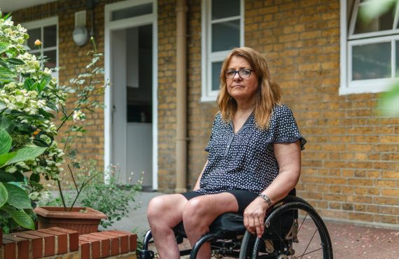 Confident woman sitting in a wheelchair beside a garden, conveying strength outdoors.
